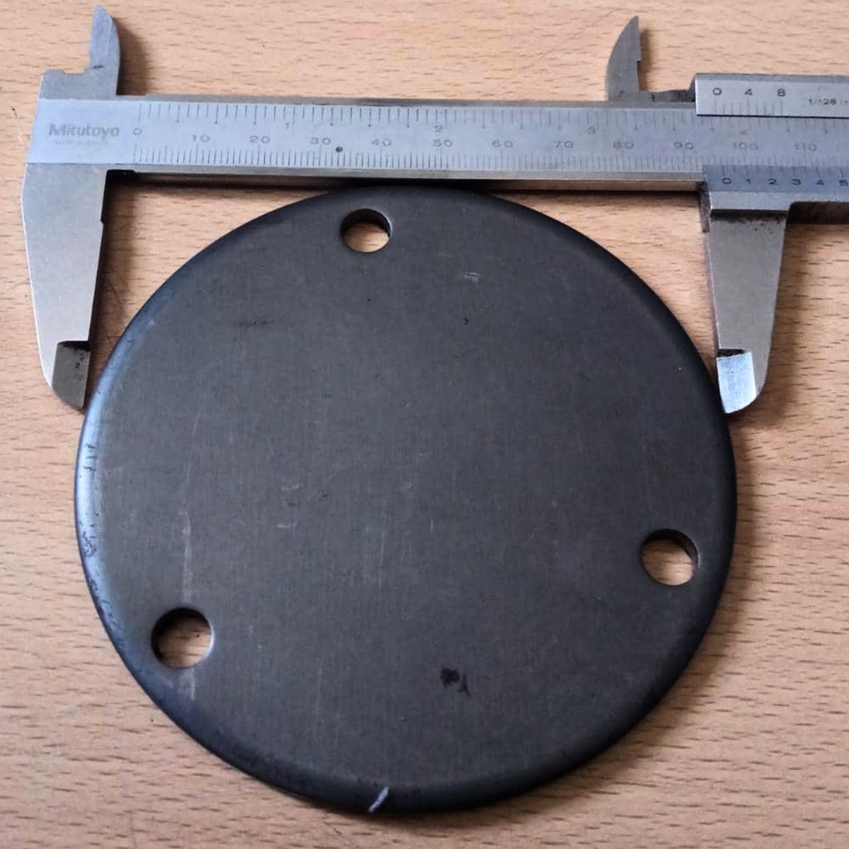 Se muestra vernier tomando el diámetro aproximado (100mm) de la base de anclaje redonda con huecos.